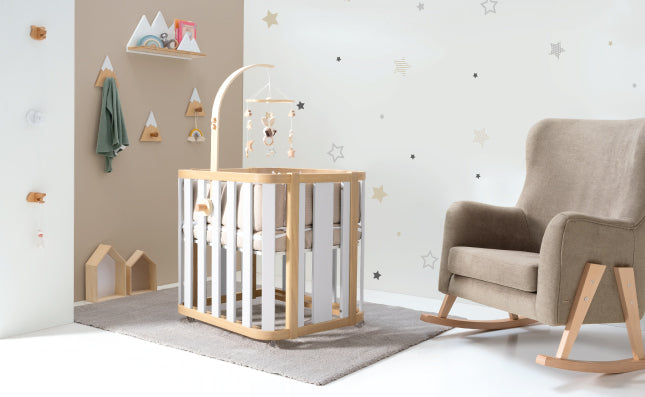 minicuna crea plus en habitación de bebé junto un sillón de lactancia