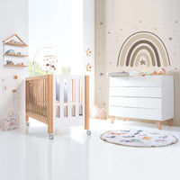 Habitación para niños en blanco y madera con cuna y cómoda